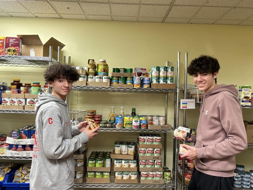 Two brothers/young male teens volunteering to stock the JFS Community Food Pantry